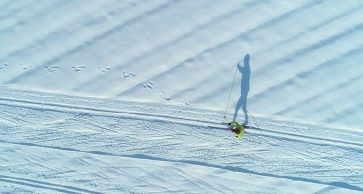 Vue aérienne d'une personne faisant du ski sur un terrain enneigé.
