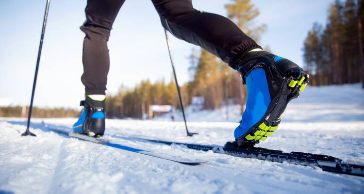 Gros plan d'une personne faisant du ski sur un sentier enneigé.