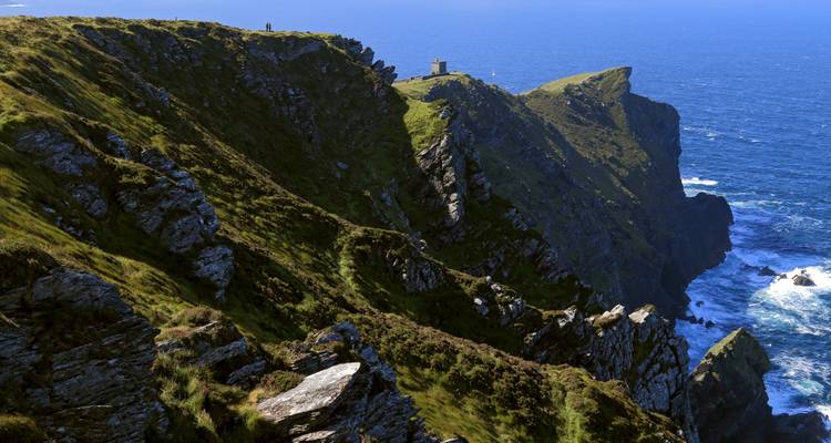 Falaises spectaculaires au bord de la mer avec un sentier de randonnée.