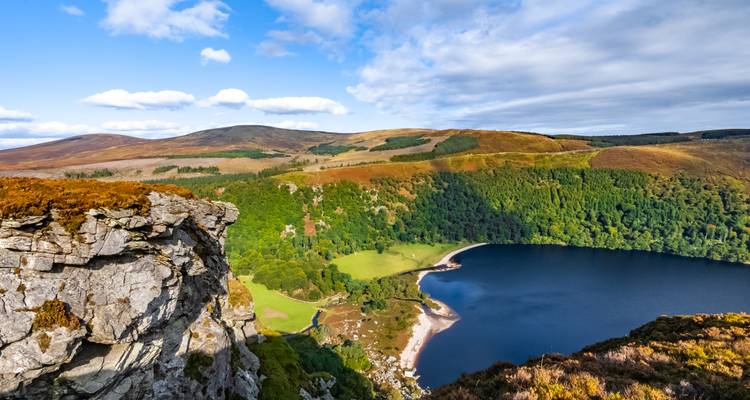 Panoramic view of a lake surrounded by lush forest and cliffs.