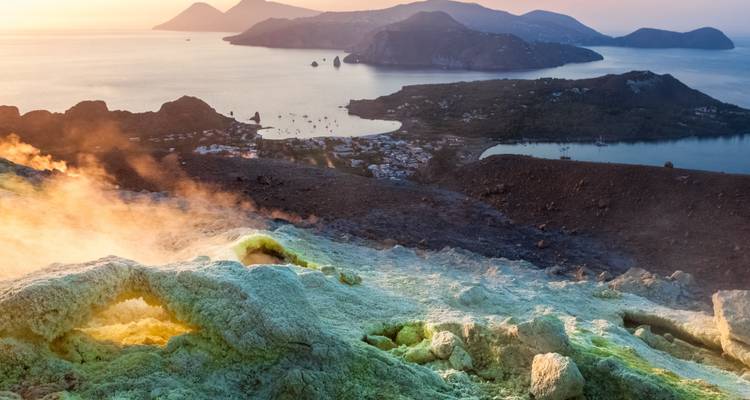 Malerische Aussicht auf vulkanische Landschaft mit bunten Mineralien und fernen Inseln.