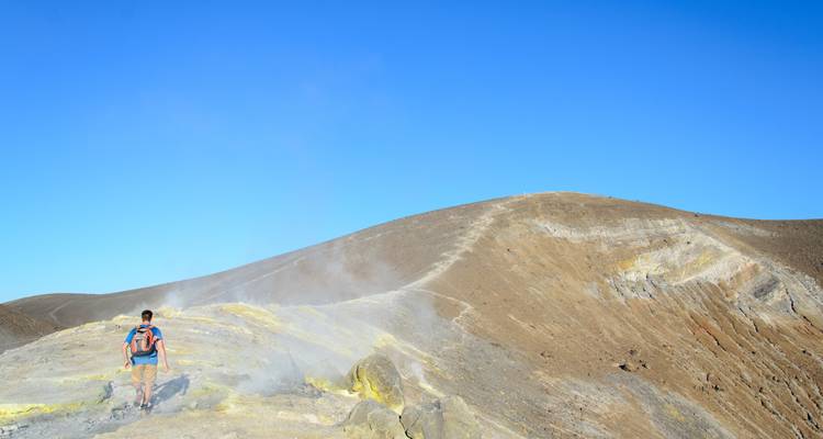 Mann wandert auf einem dampfenden Vulkanberg.