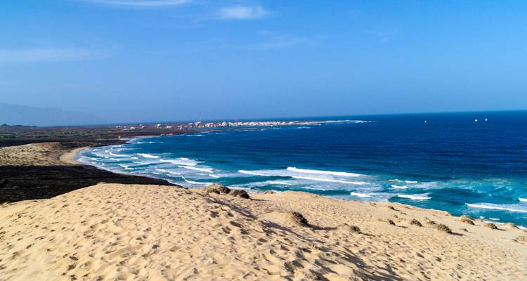 Golden sand dune overlooking a sweeping crescent of deep-blue Atlantic surf.