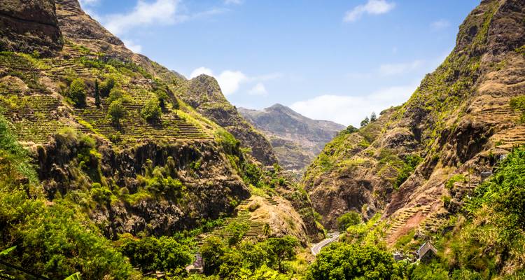 Verdant terraced valleys and sharp ridges under a bright blue Cape Verde sky.