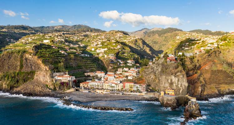 Cliff-top coastal village with terraced fields cascading toward the Atlantic waves.