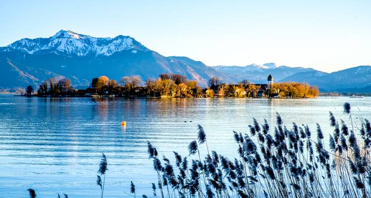 Vue panoramique d'un lac avec une île et des montagnes enneigées en arrière-plan.