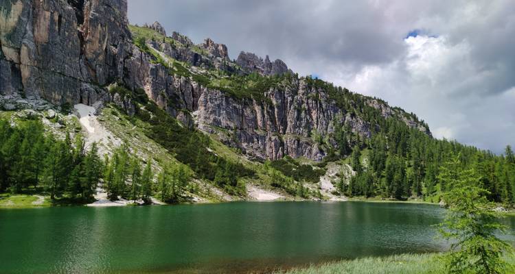 Lake surrounded by rocky mountains and lush forest.