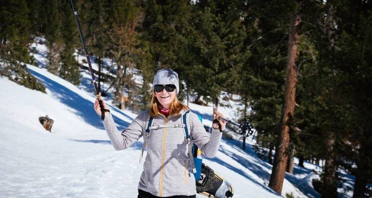 Une femme profitant d'une randonnée enneigée dans un cadre forestier.