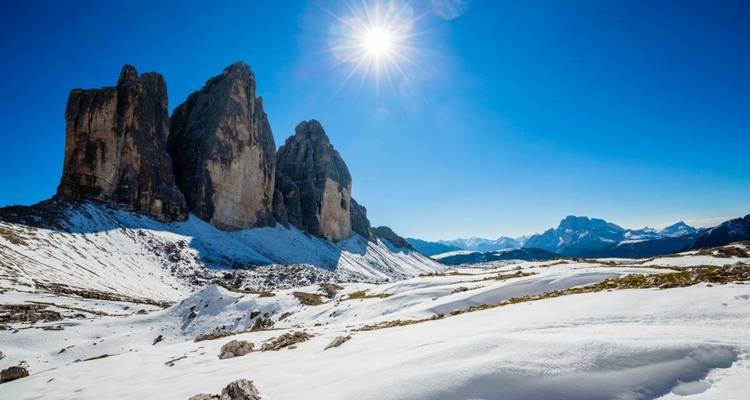 The Tre Cime di Lavaredo, a famous mountain group, under a bright sun.