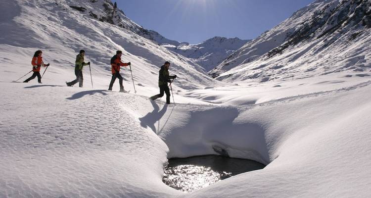 Groupe de personnes faisant de la randonnée sur un sentier de montagne enneigé.
