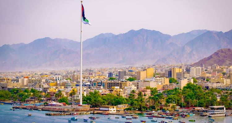 Aqaba-Stadtbild mit einem großen Fahnenmast und Bergen im Hintergrund.
