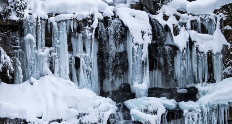 Cascade gelée et stalactites de glace couvertes de neige.