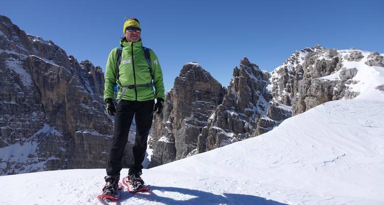 Personne debout sur la neige avec des pics montagneux escarpés en arrière-plan.