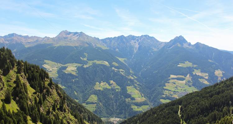 Vista de un valle montañoso con bosques y praderas.