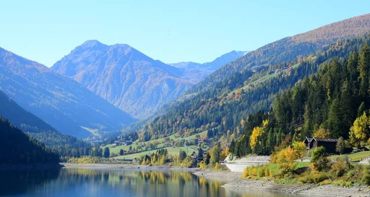 Lago rodeado de árboles otoñales coloridos y montañas.