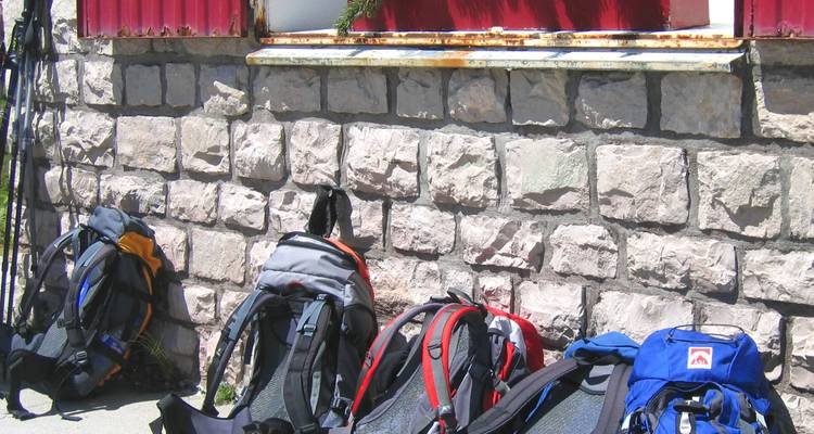 Une rangée de sacs à dos alignés contre un bâtiment en pierre.