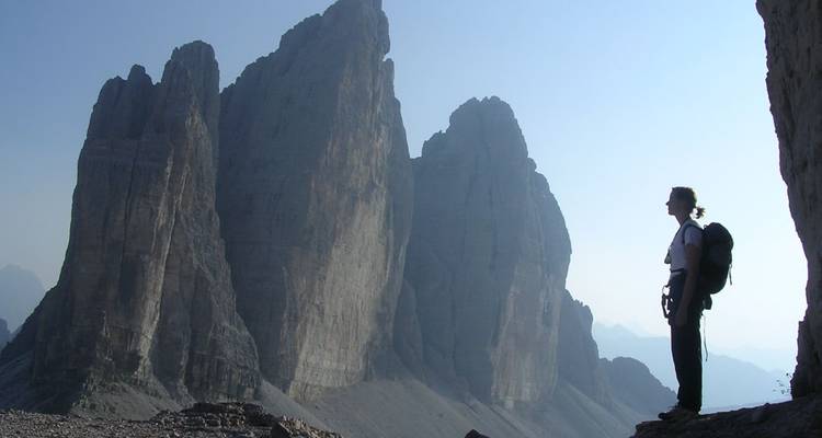 Silhouette d'un randonneur contre les imposantes formations rocheuses de Tre Cime.