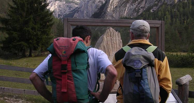 Deux randonneurs avec des sacs à dos regardant une formation rocheuse naturelle.