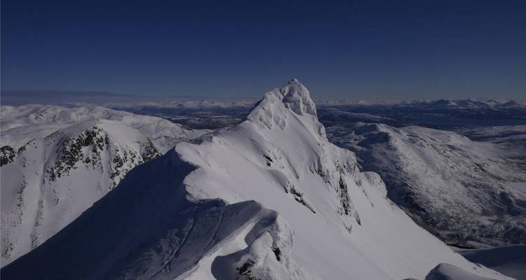 Pic de montagne spectaculaire couvert de neige contre un ciel dégagé.