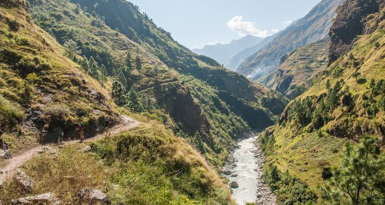 Abenteurer wandern entlang eines Flusses durch eine bergige Landschaft.