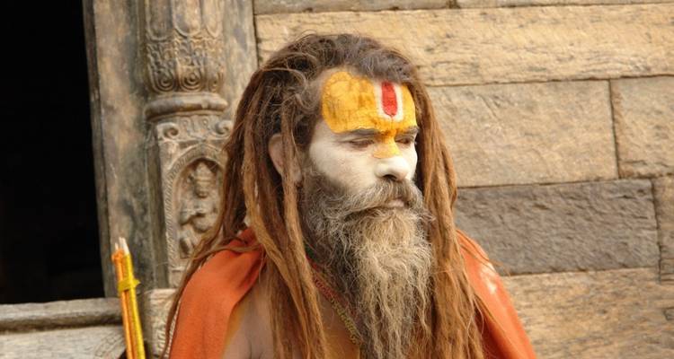 Heiliger Mann mit bemaltem Gesicht und Dreadlocks sitzend.