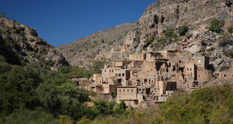 Hillside village with stone buildings amidst rocky terrain.