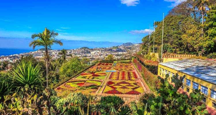 Parterres geométricos coloridos del Jardín Botánico de Madeira con vista a Funchal y el mar.