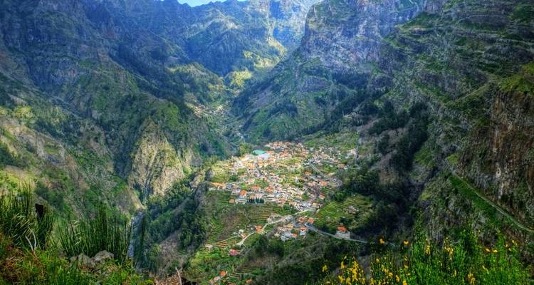 Village nestled in a valley surrounded by high cliffs and lush vegetation.