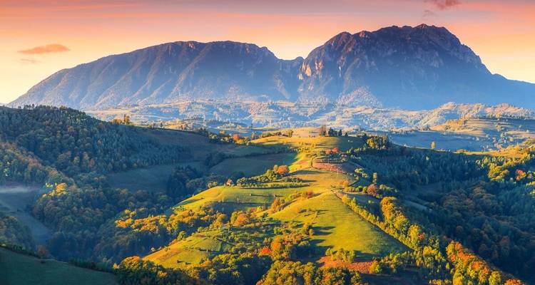 Een schilderachtig uitzicht op groene heuvels met een grote berg op de achtergrond.