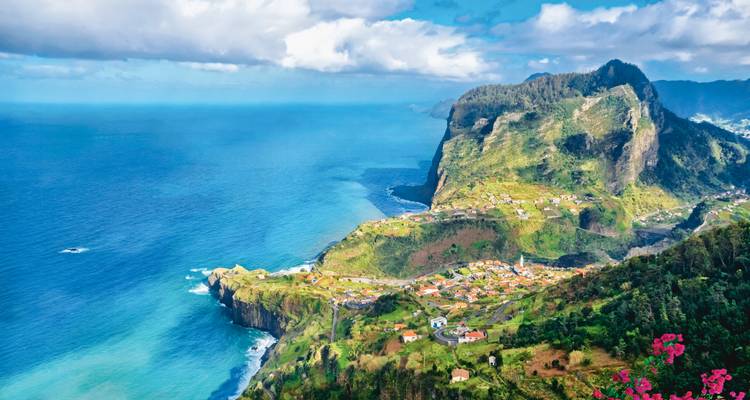 Dramatische kustrotsen en dorpen van Madeira onder heldere blauwe luchten.