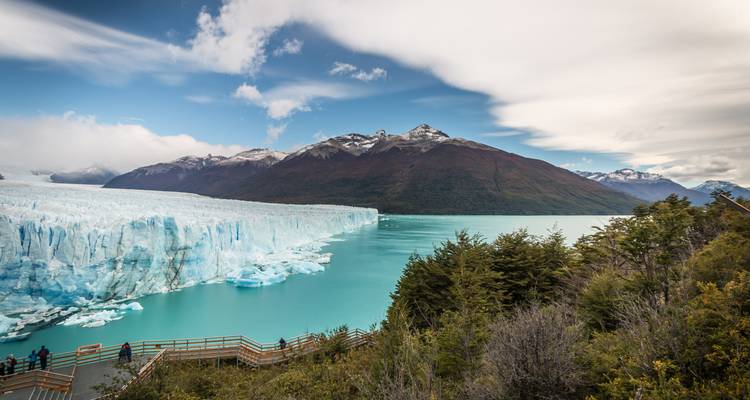Grand glacier rencontrant un lac turquoise avec des gens sur une promenade en bois.