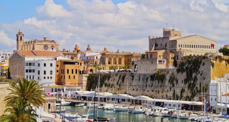 Historischer Hafen von Ciutadella mit Yachten, mittelalterlichen Wällen und farbenfrohen mediterranen Gebäuden.