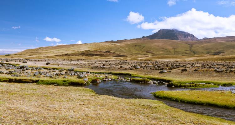 Open landscape with a stream and distant mountains.