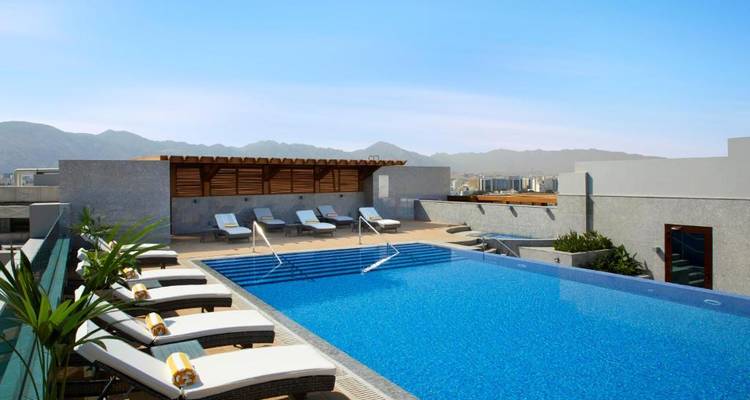 Piscina infinita en azotea with hamacas y vistas a la ciudad y las montañas.