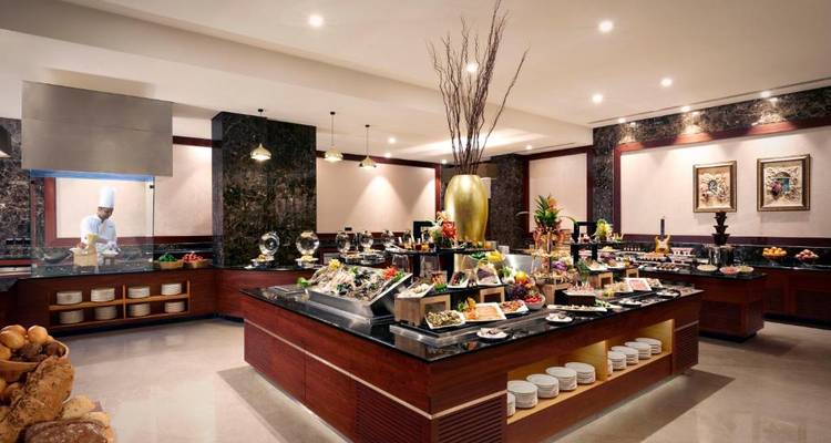 Área de buffet con una gran variedad de platos y un chef visible al fondo.