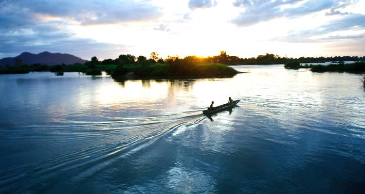Un bateau glissant sur une rivière au coucher du soleil.