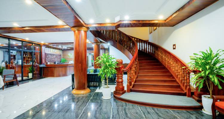 Hall d'entrée intérieur avec un grand escalier en bois et des plantes.
