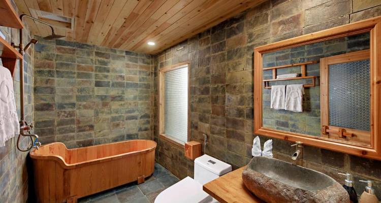 Rustieke badkamer met houten badkuip en stenen muren.