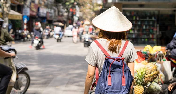Person mit Rucksack, die durch einen Straßenmarkt geht.