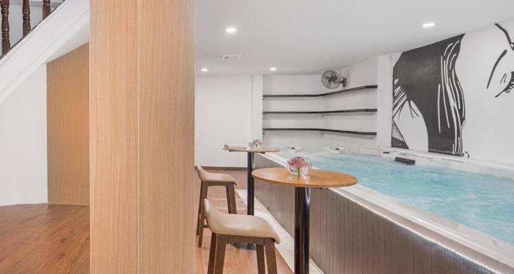 Binnenzwembad met een spabad naast hoge stoelen en een muurschildering.