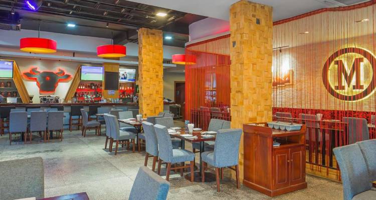 Restaurantinterieur met eettafels, een bar en mensen die dineren.