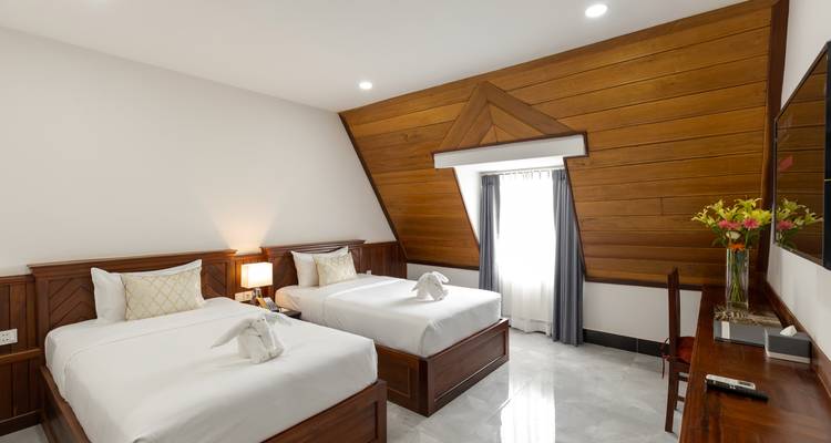 Chambre d'hôtel avec lits jumeaux et murs lambrissés de bois.