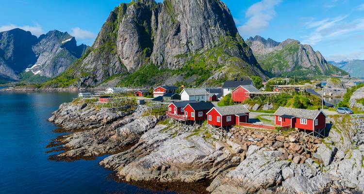 Dramatisch bergachtergrond met traditionele rode visserhuisjes op rotsachtige oevers in de Lofoten eilanden.