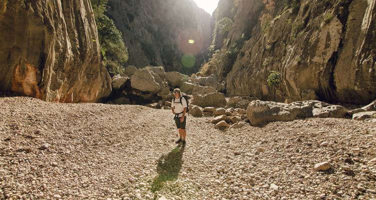 Une personne dans une gorge rocheuse avec la lumière du soleil qui filtre à travers.