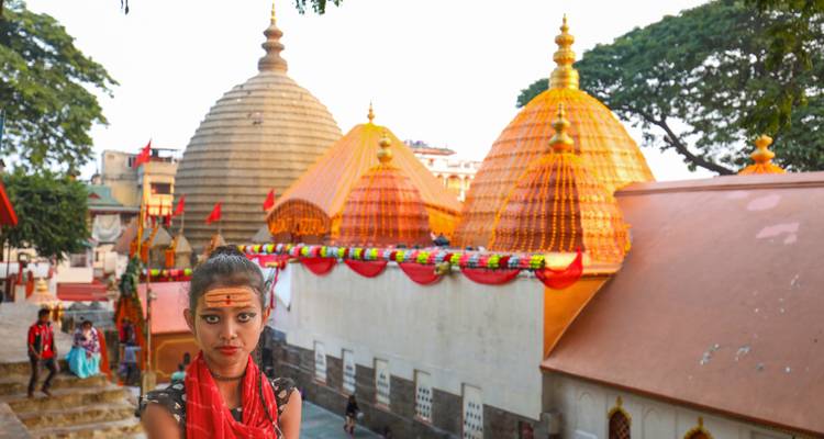 Kleurrijke tempel met versierde koepels en mensen eromheen.