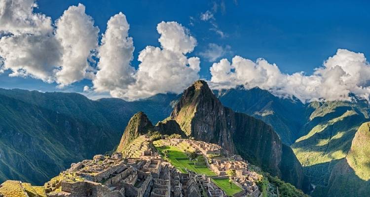 Panoramablick auf Machu Picchu mit Bergkulisse unter einem klaren blauen Himmel.