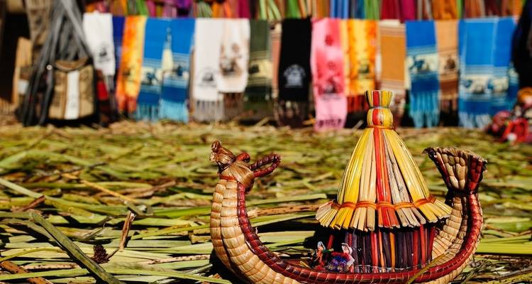 Handgemaakte boot op een rieten oppervlak met kleurrijke textiel op de achtergrond.