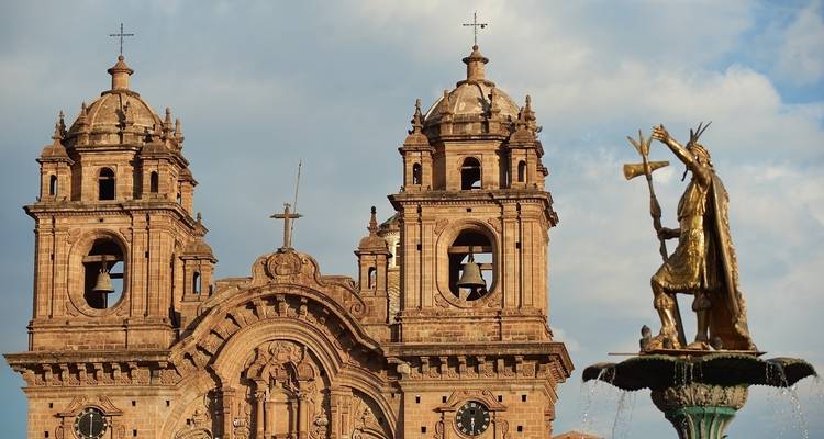 Historische kathedraal met gouden beeldfontein op de voorgrond.