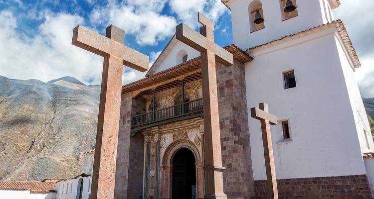 Kerk met drie grote kruizen en schilderachtige bergachtergrond.