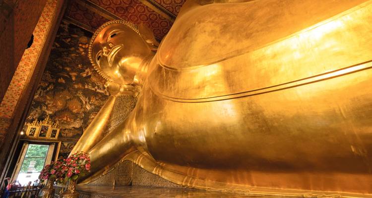 Statue dorée du Bouddha couché s'étendant à travers une salle ornée au Wat Pho.